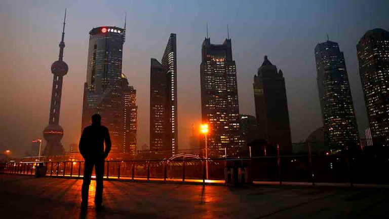 A man looks at the Pudong financial district of Shanghai November 20, 2013.