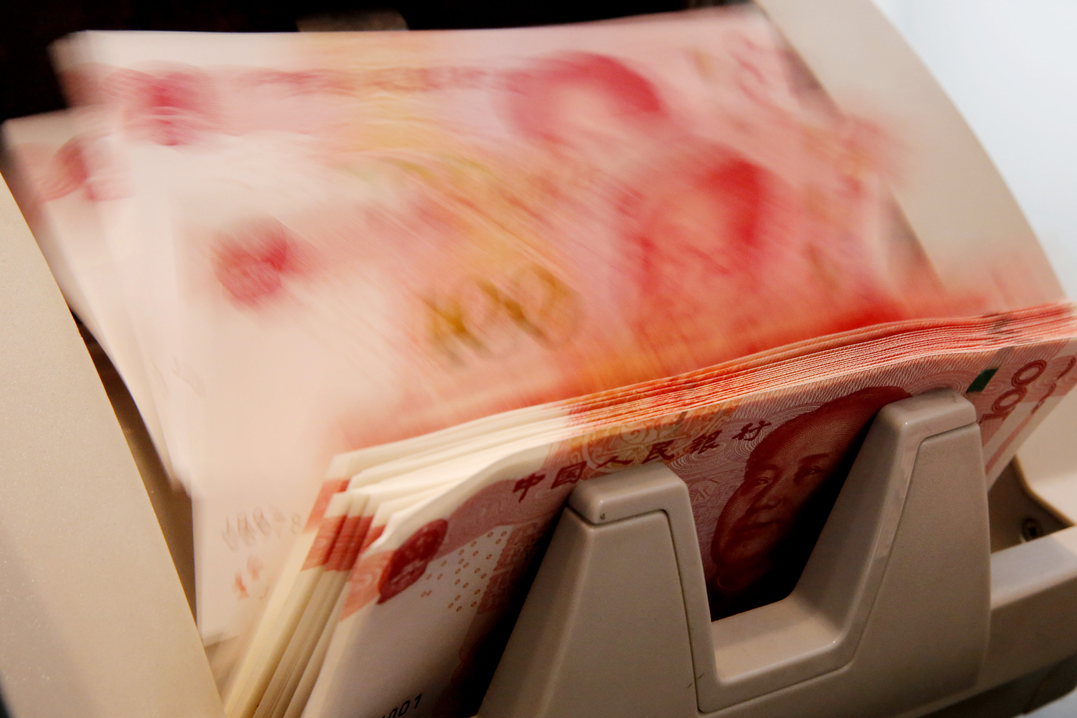 Chinese 100 yuan banknotes are seen in a counting machine while a clerk counts them at a branch of a commercial bank in Beijing, China, March 30, 2016.