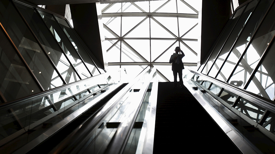 A man scratching his head rides on an escalator at a business district in Tokyo, Japan, May 25, 2015.